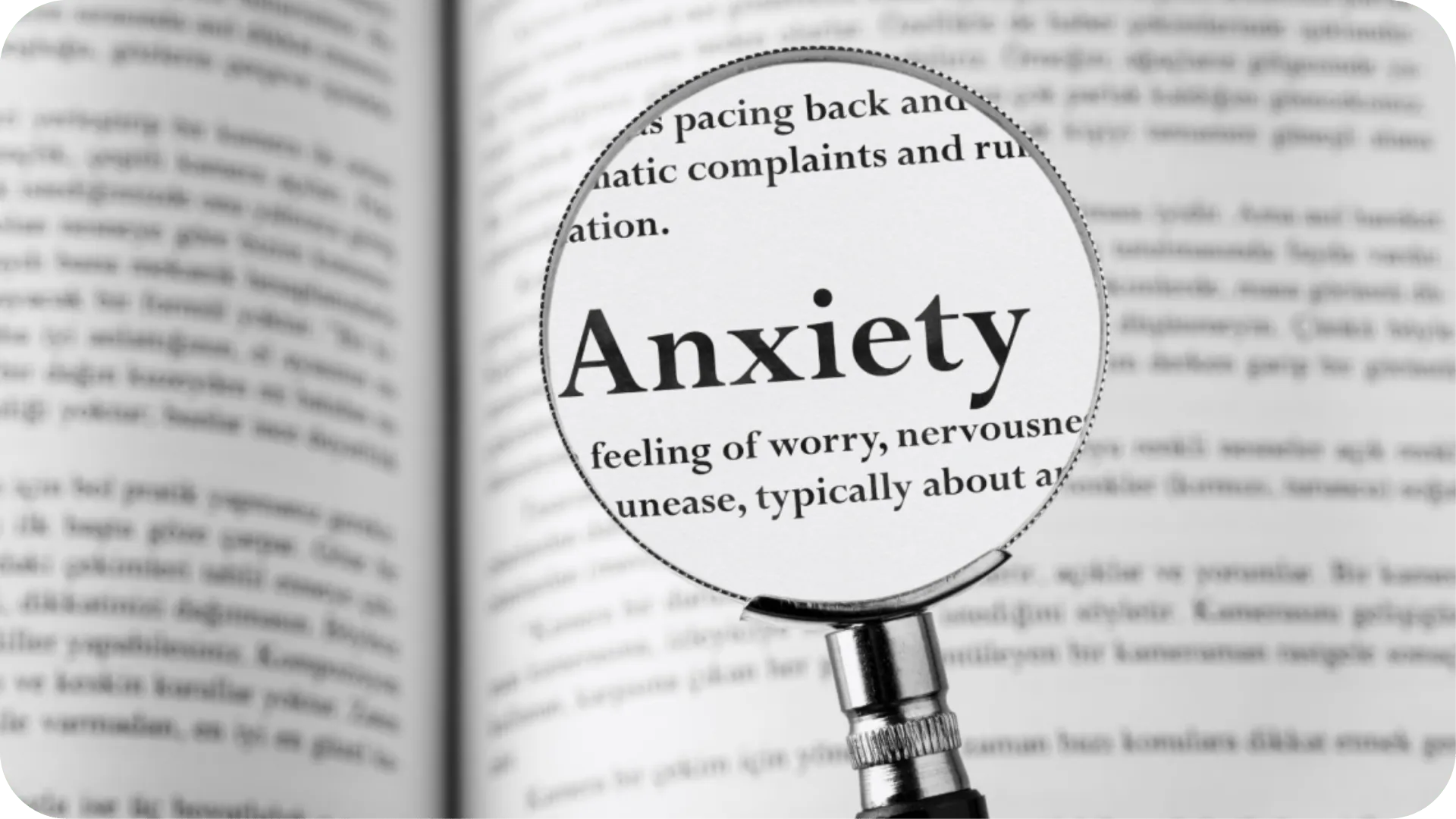 A blurred page of text with a magnifying glass focusing on the word 'anxiety'.