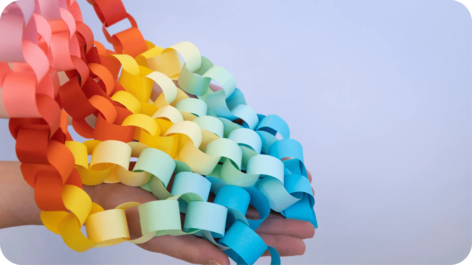 Photograph of multi-coloured paper chains falling onto a hand.